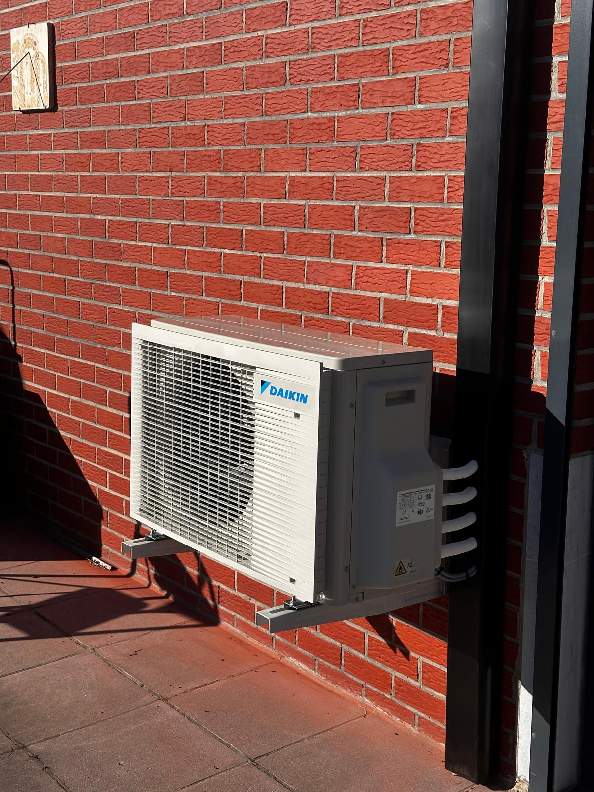 Unité extérieure Daikin fixée sur façade en briques rouges