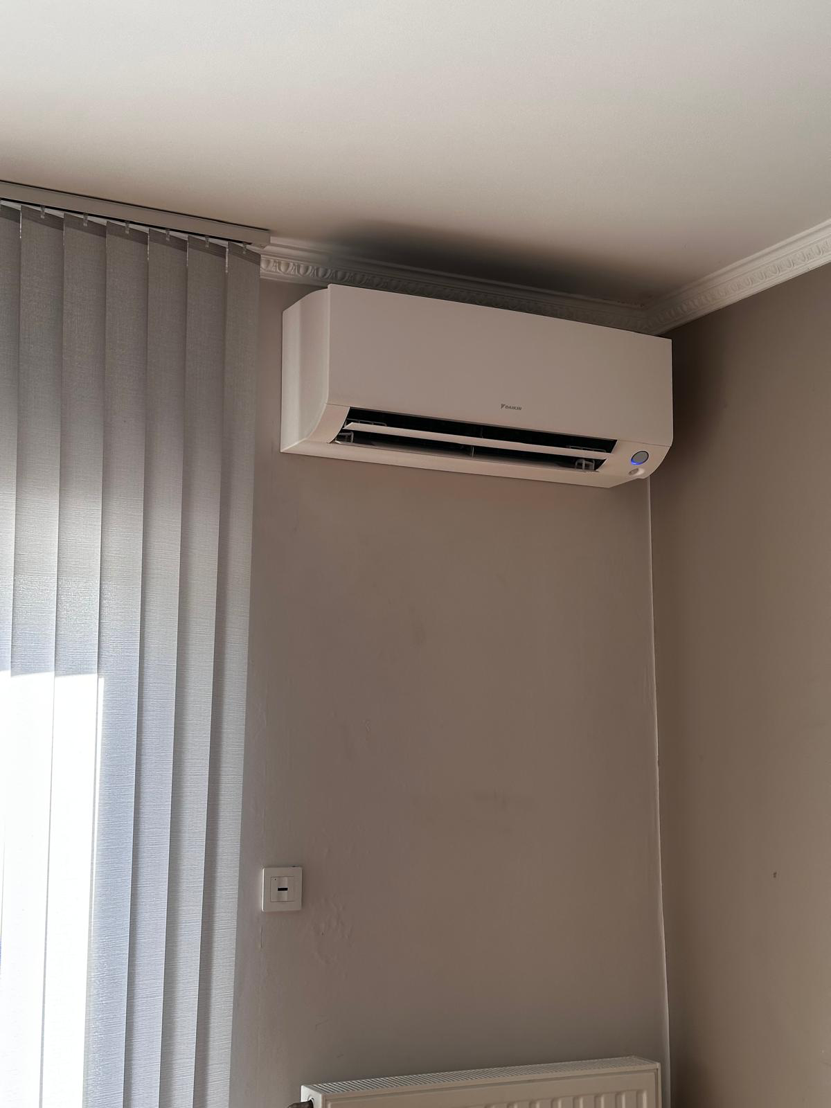 Split mural Daikin installé dans une pièce de vie avec stores
